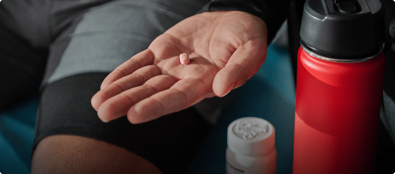 A hand holding a pill.