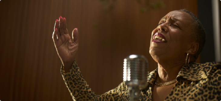 Denise is belting a song into a microphone.