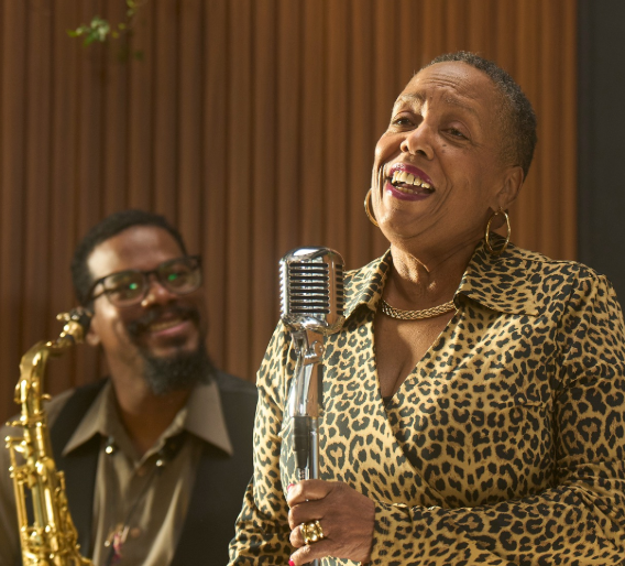 Denise is singing into a microphone.