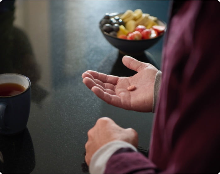 A man holding a pill in his hand.