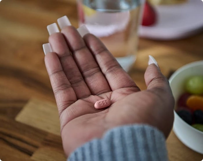A woman holding a pill in her hand.