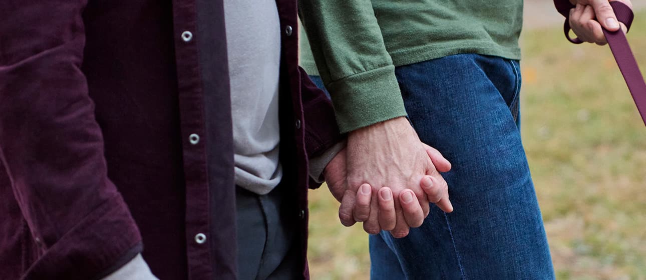 A couple holding hands outside.