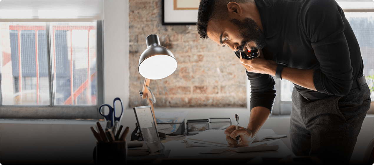 Dimitri is writing something while on the phone.