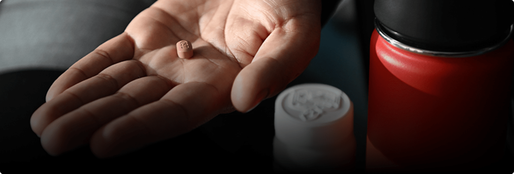 A hand holding a pill.