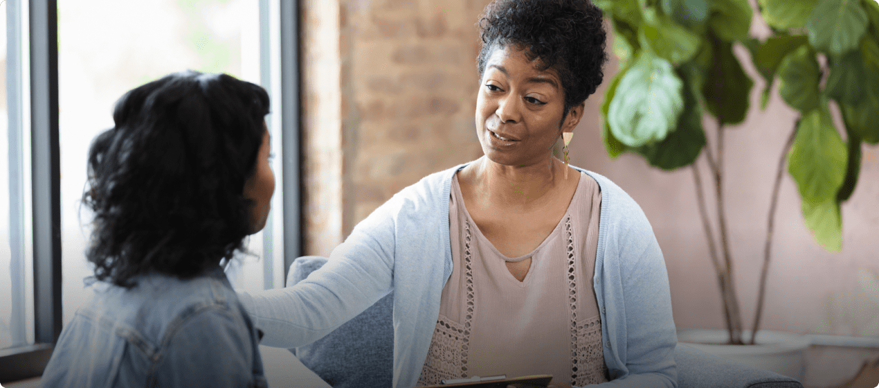 A woman talking with someone while having her hand on her shoulder.