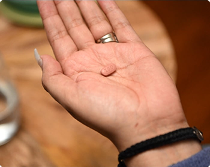 A hand holding a small pill.